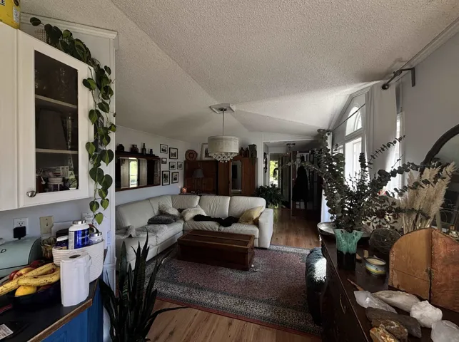 Living area featuring wood finished floors, vaulted ceiling, and a textured ceiling