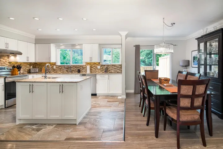 Kitchen with stainless steel appliances, a sink, healthy amount of natural light, white cabinetry, and crown molding