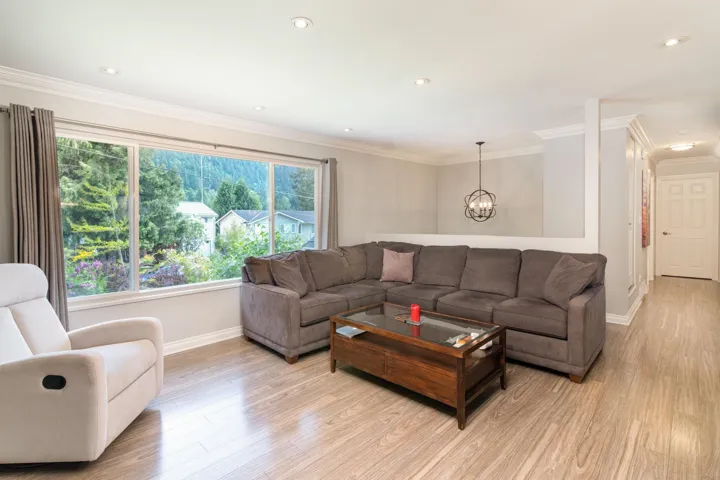 Living room featuring baseboards, light wood-style floors, a chandelier, ornamental molding, and recessed lighting