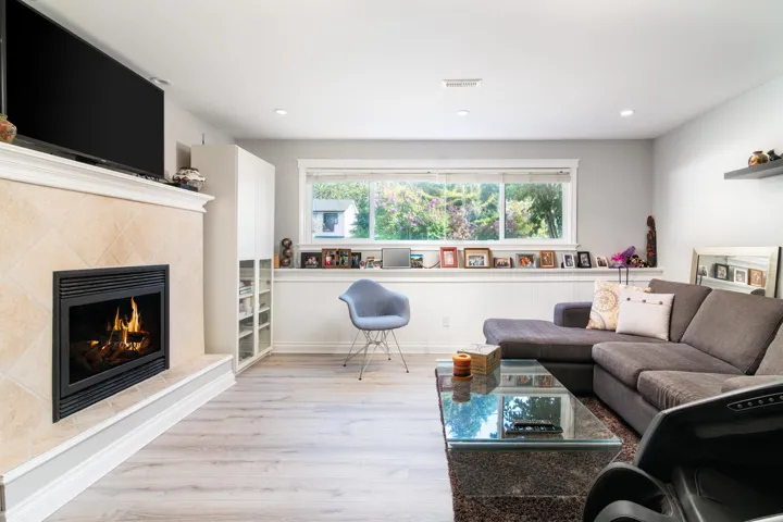 Living room featuring wood finished floors, a premium fireplace, and recessed lighting
