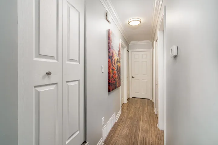 Hallway featuring wood finished floors, crown molding, and baseboards