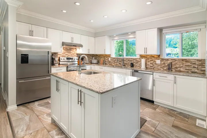 Kitchen featuring stainless steel appliances, under cabinet range hood, a sink, recessed lighting, and a kitchen island with sink