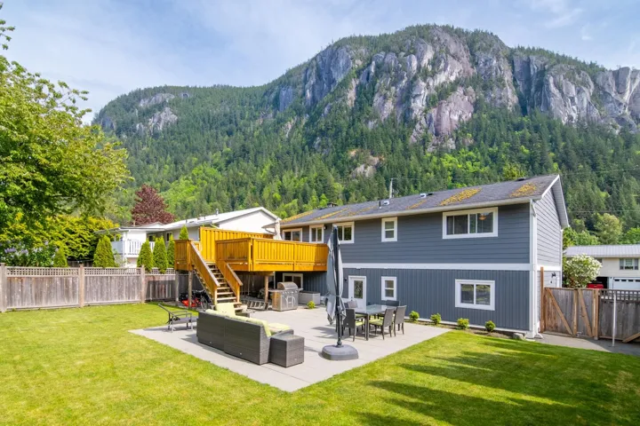 Back of house with a deck with mountain view, stairway, a patio, and a view of trees