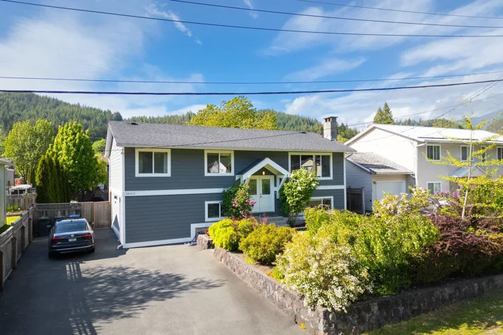 Raised ranch featuring asphalt driveway and a chimney