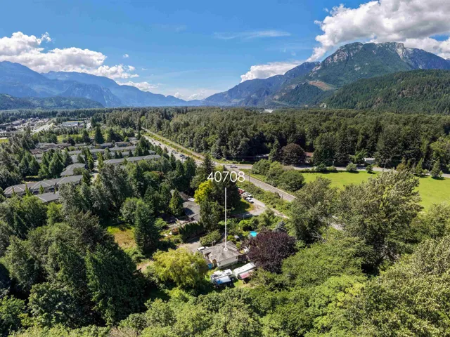 Aerial perspective showcasing a property surrounded by mature trees, a paved road, and a verdant landscape