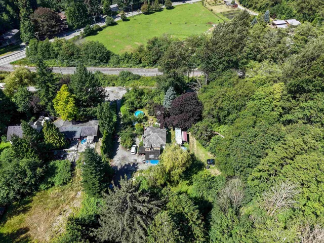 Expansive property featuring dense mature trees and a residential structure with a shingle roof