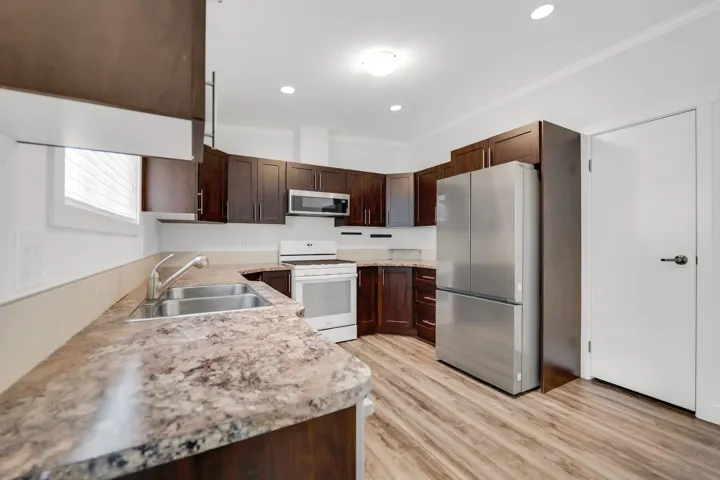Kitchen featuring appliances with stainless steel finishes, a sink, crown molding, light countertops, and dark brown cabinets