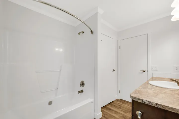 Bathroom with crown molding, bathing tub / shower combination, wood finished floors, and vanity
