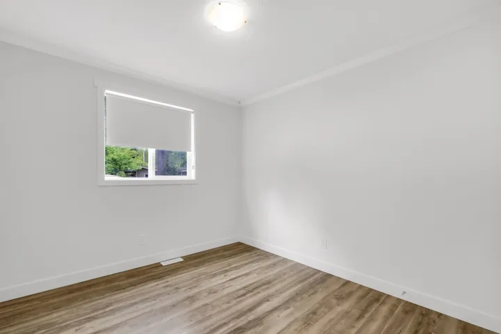 Empty room featuring crown molding, baseboards, and wood finished floors