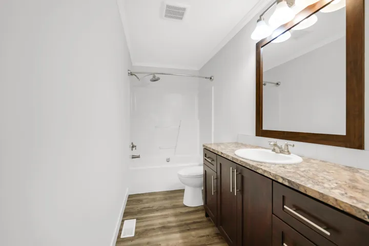 Full bathroom with crown molding, vanity, wood finished floors, bathing tub / shower combination, and toilet