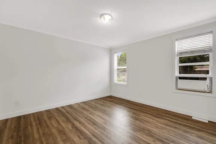 Empty room with crown molding, wood finished floors, and baseboards