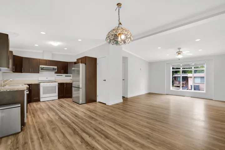 Kitchen featuring appliances with stainless steel finishes, light wood-style floors, dark brown cabinetry, open floor plan, and recessed lighting