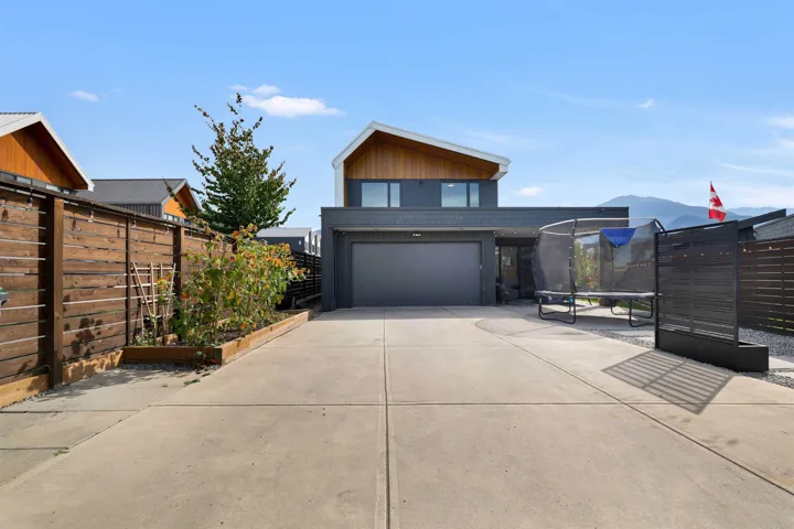 Modern home featuring a trampoline, a vegetable garden, concrete driveway, and an attached garage