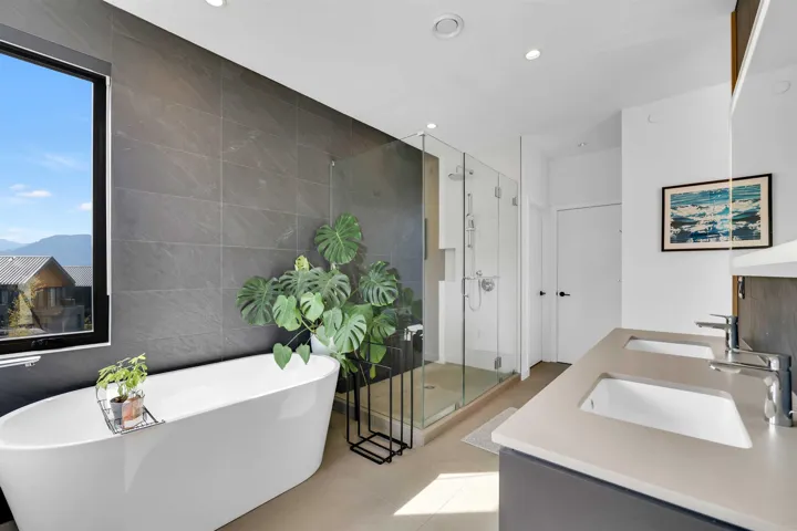 Full bath with tile walls, a stall shower, a soaking tub, double vanity, and recessed lighting