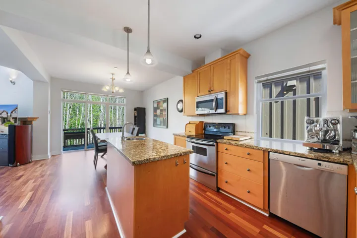 Kitchen with stainless steel appliances, decorative backsplash, wood finished floors, and a chandelier