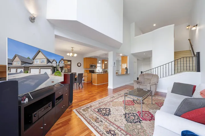 Living room featuring a chandelier, light wood finished floors, a towering ceiling, and stairway