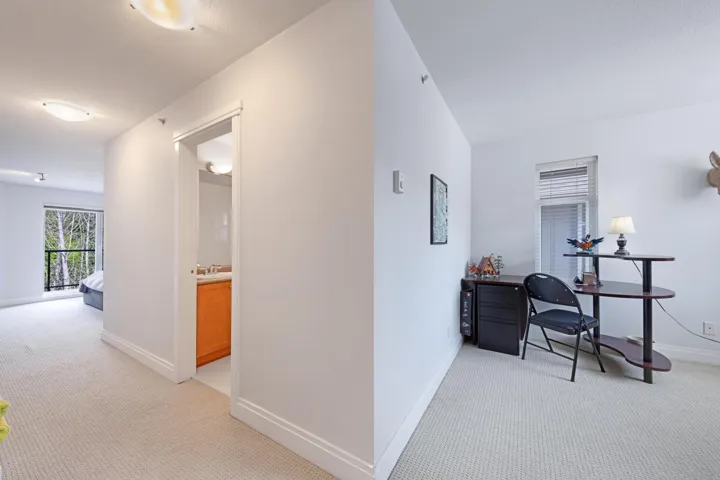 Hallway with light carpet, a sink, and baseboards