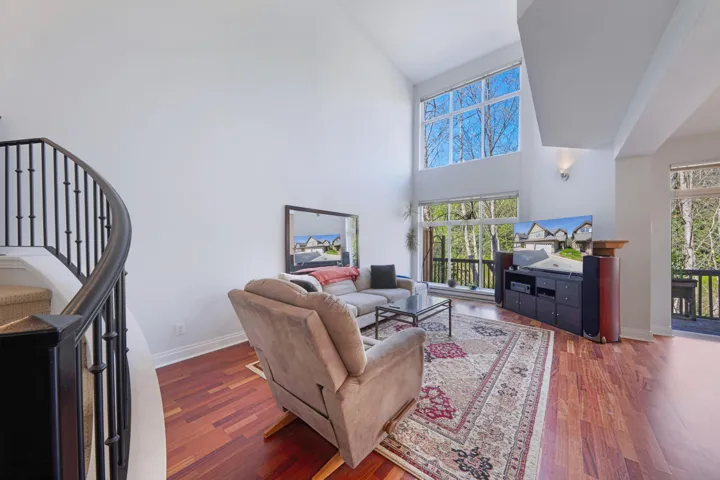Living room with high vaulted ceiling, wood finished floors, and baseboards