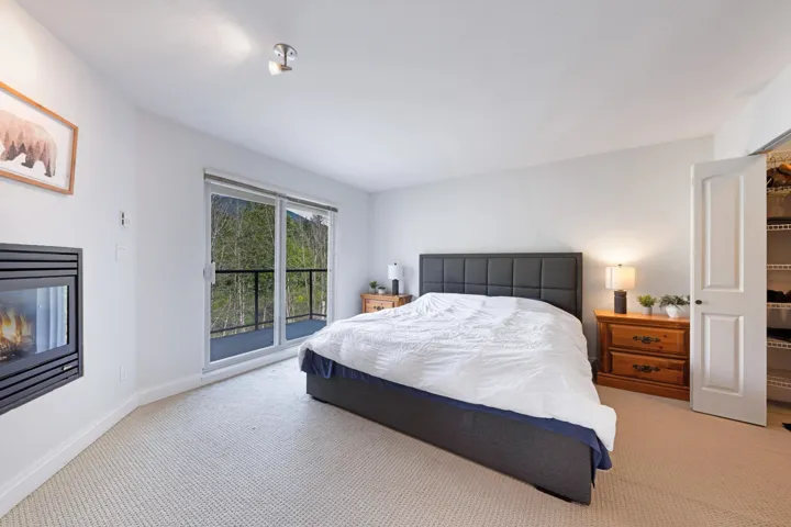 Bedroom featuring light colored carpet, access to outside, baseboards, and a glass covered fireplace