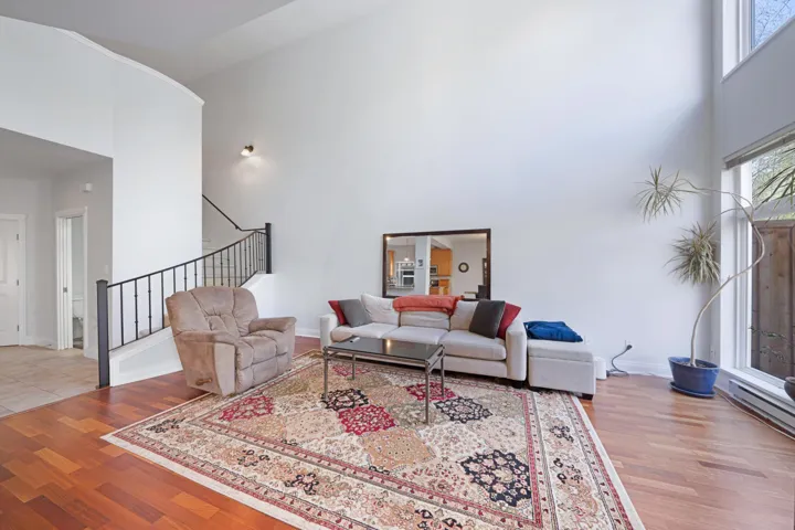 Living room featuring a towering ceiling, stairs, wood finished floors, and baseboards