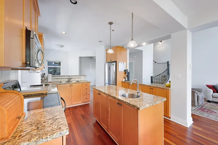Kitchen with a sink, appliances with stainless steel finishes, dark wood-style floors, a center island with sink, and recessed lighting