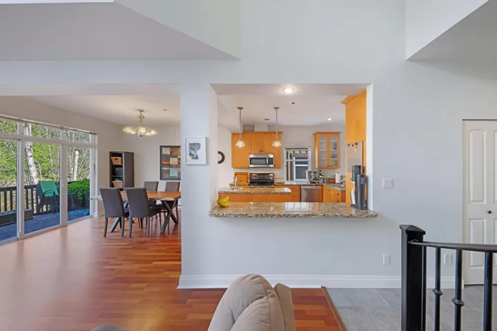 Kitchen featuring stainless steel appliances, wood finished floors, a chandelier, glass insert cabinets, and light stone counters