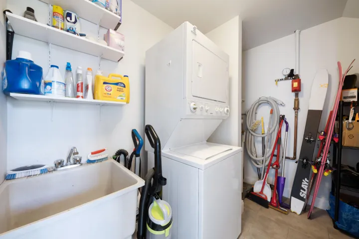Washroom featuring stacked washing machine and dryer and light tile patterned floors