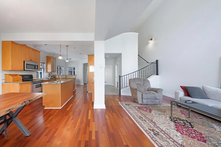 Kitchen with appliances with stainless steel finishes, open floor plan, a kitchen island with sink, and wood finished floors
