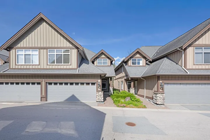 View of front of property featuring roof with shingles, board and batten siding, stone siding, and driveway