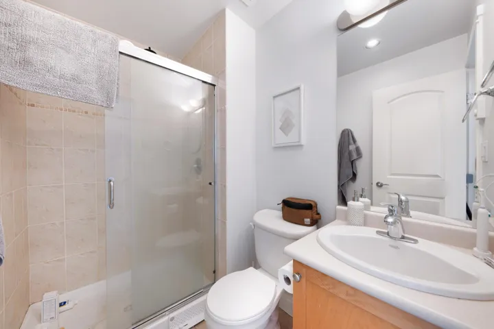 Bathroom with vanity, toilet, and a stall shower