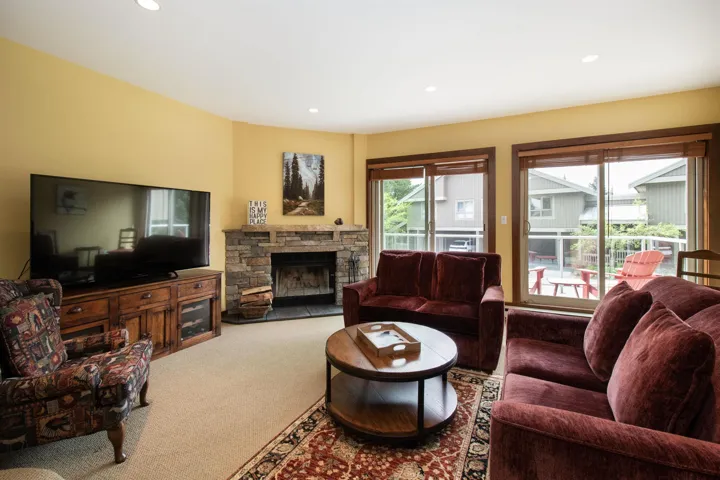 Living area featuring a stone-clad fireplace, recessed lighting, and two sliding glass doors opening to an outdoor area