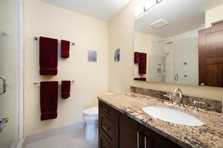 Bathroom featuring a dark wood vanity with a granite countertop and an undermount sink
