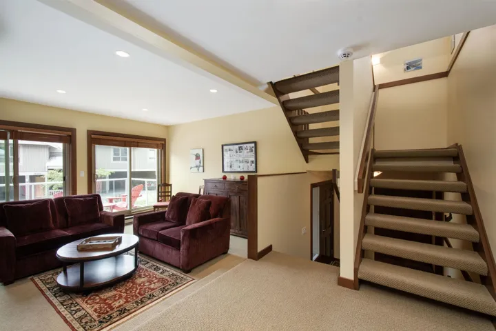 Living area featuring recessed lighting, two sliding glass doors with wood trim, and a multi-level staircase with carpeted treads and wood handrails