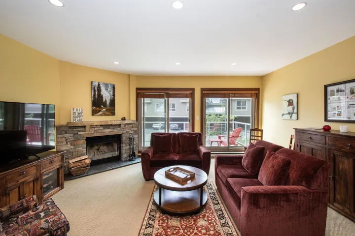 Living area featuring a stone-clad fireplace, recessed lighting, and a glass sliding door leading to an outdoor space