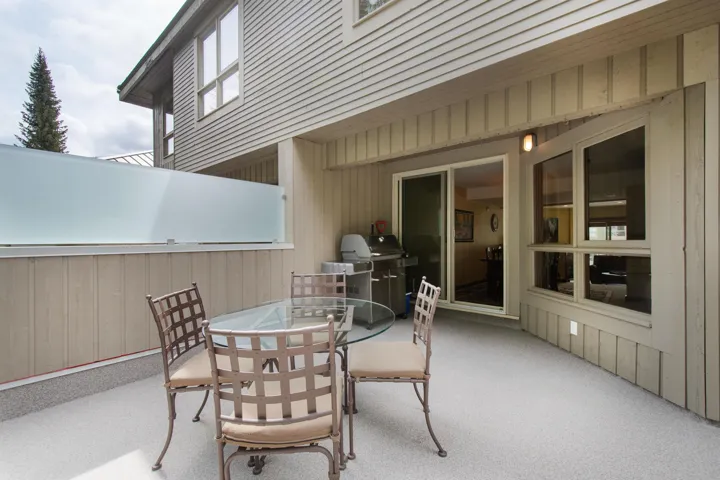 Spacious patio featuring a gray speckled surface, frosted privacy barrier, and direct access through a sliding glass door