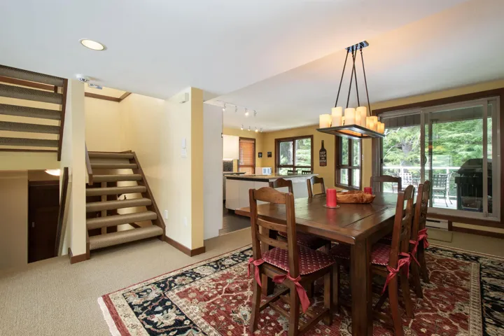 Open-concept dining area featuring a candelabra-style chandelier, light-colored walls, and a glass sliding door leading to an outdoor space
