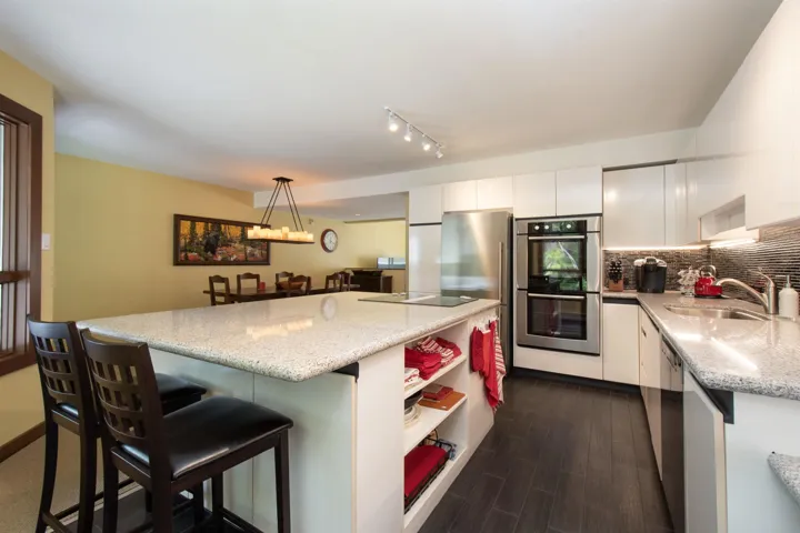 Contemporary kitchen featuring an expansive center island with seating, a smooth cooktop, and built-in shelving