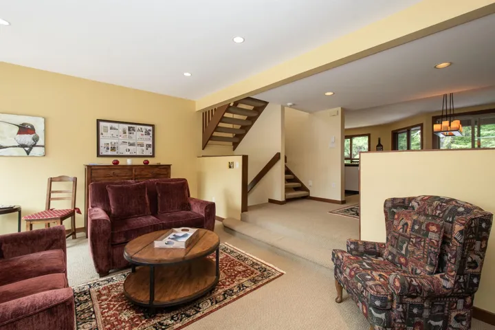 Living area featuring recessed lighting, a built-in wood staircase with railing, and a partial wall separating spaces