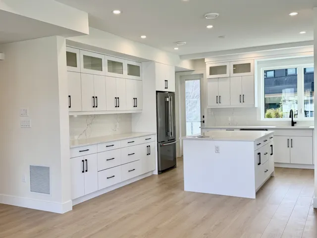 Kitchen featuring glass insert cabinets, white cabinets, a center island, high quality fridge, and recessed lighting