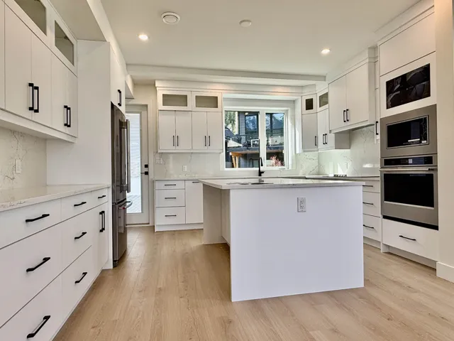 Kitchen with glass insert cabinets, a kitchen island, white cabinets, backsplash, and recessed lighting