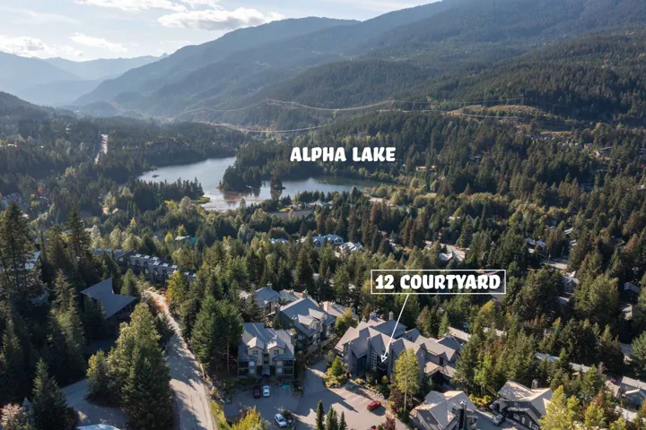 Aerial view of property and surrounding area with a water and mountain view and a forest