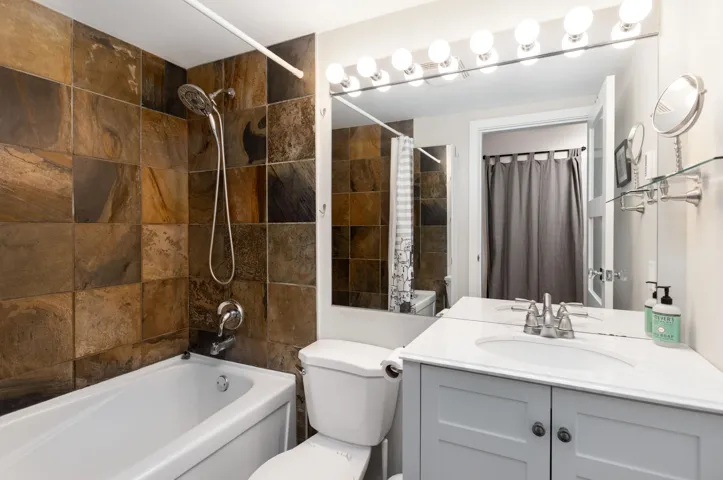 Full bathroom with shower / tub combo with curtain and vanity