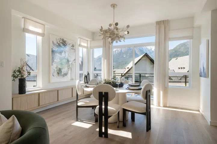 Expansive windows, light wood-finish flooring, built-in lower cabinetry, and a modern chandelier