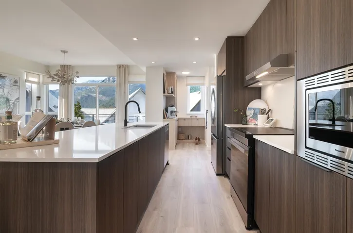 Modern kitchen featuring wood-finish cabinetry, light-toned countertops, a stainless steel appliance package, and light wood-finish flooring