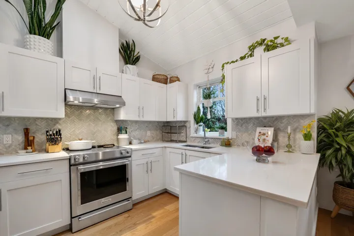 Kitchen with stainless steel range with electric cooktop, a peninsula, light wood-style flooring, vaulted ceiling, and white cabinetry