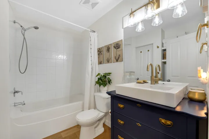 Bathroom with vanity, shower / bath combination with curtain, and light wood finished floors