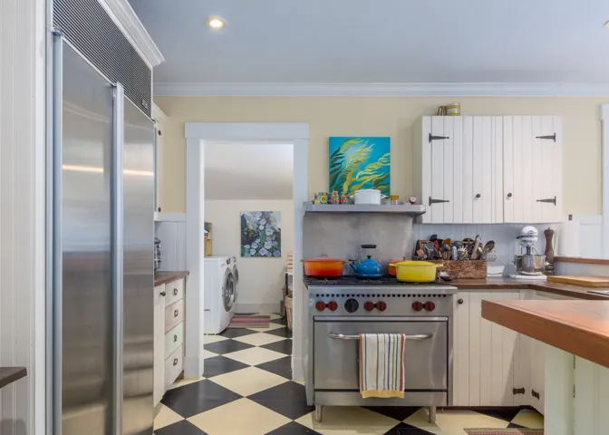 Kitchen with light floors, white cabinets, dark countertops, high quality appliances, and washing machine and dryer