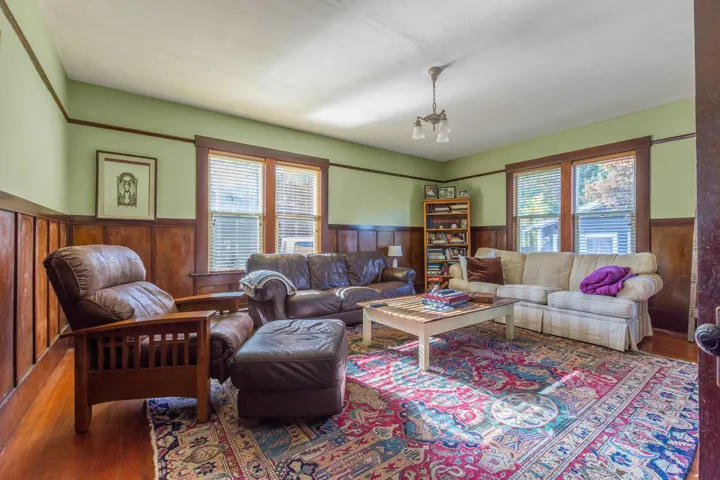 Living area with wood walls, a wainscoted wall, plenty of natural light, and wood finished floors