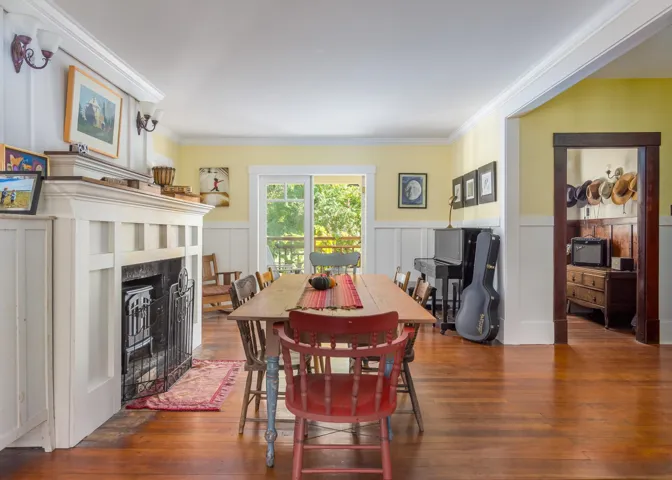 Dining area with a fireplace with flush hearth, hardwood / wood-style floors, ornamental molding, and a wainscoted wall