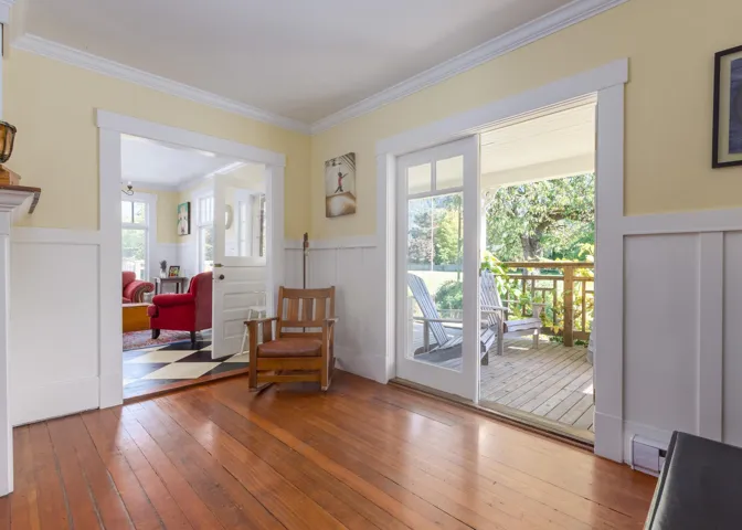 Living area with visible vents, a decorative wall, crown molding, a wainscoted wall, and hardwood / wood-style floors